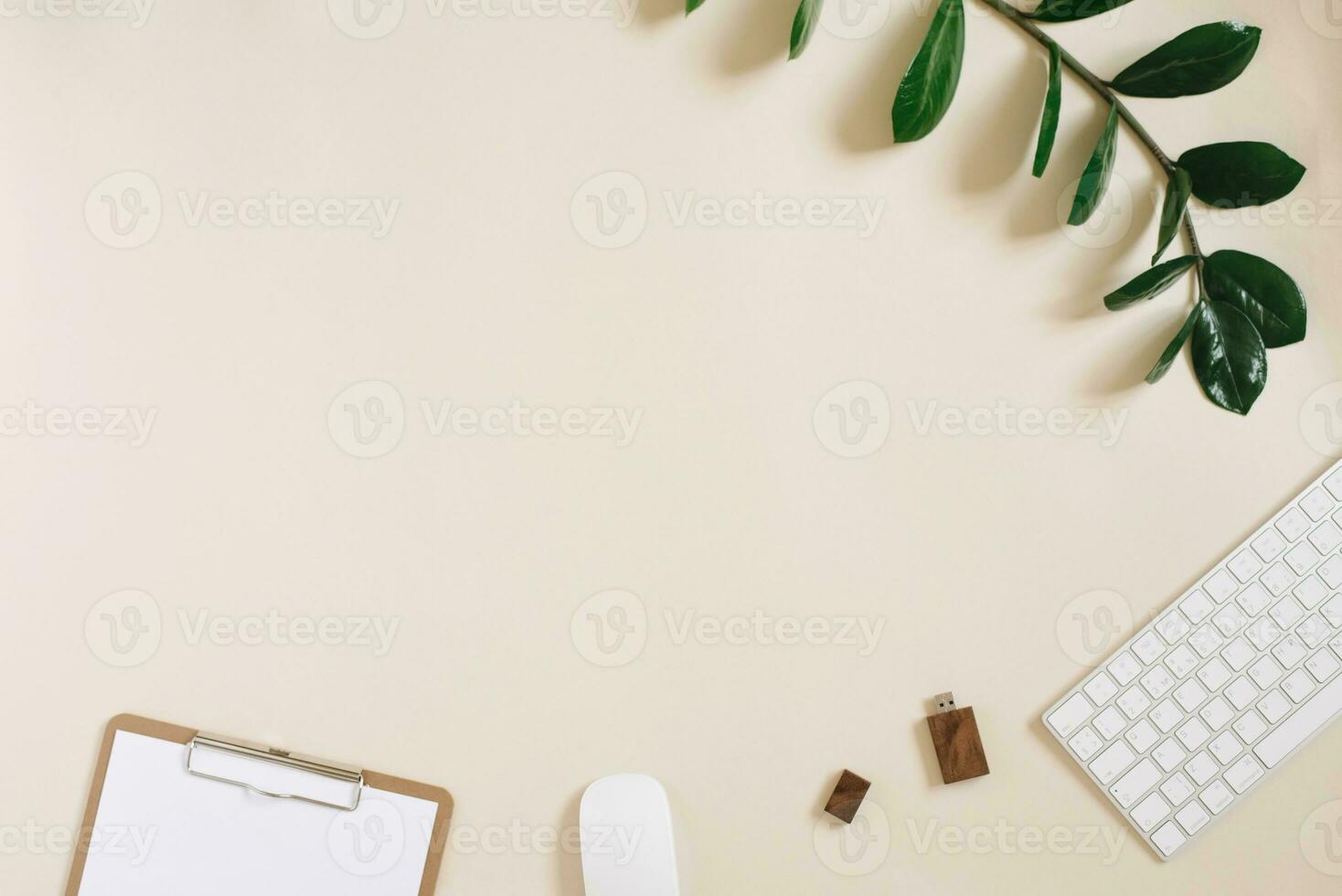 Modern desktop of a freelancer or blogger with a keyboard, mouse, pen, usb drive and Notepad with a blank sheet of paper on a light beige background with space copying. Flat lay photo