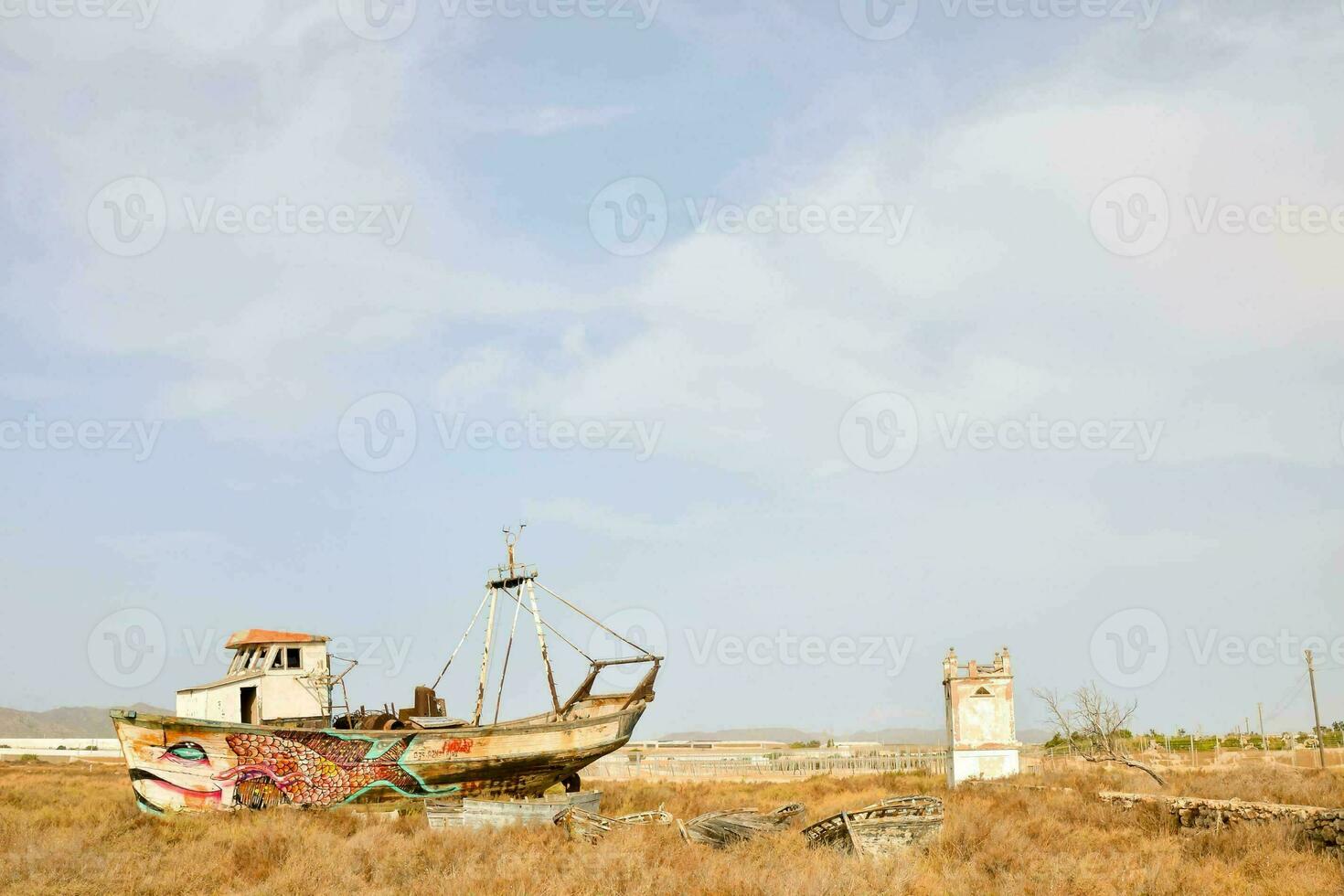 an old boat sits in a dry field photo