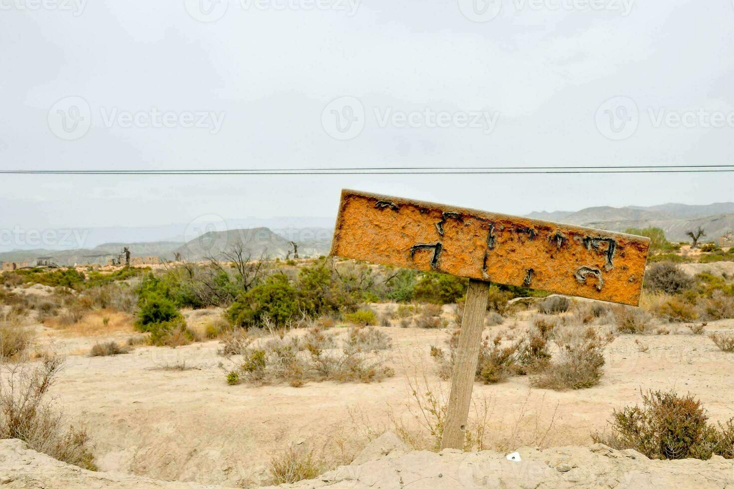 a sign in the desert with a wooden post photo