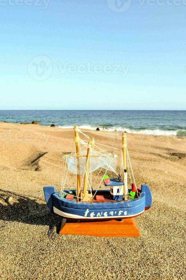 a toy boat on the beach near the ocean photo