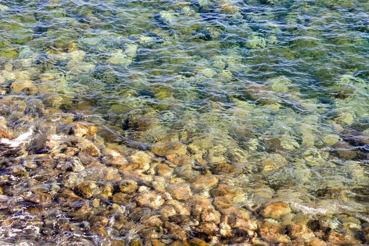 el agua es claro y azul con rocas y guijarros foto