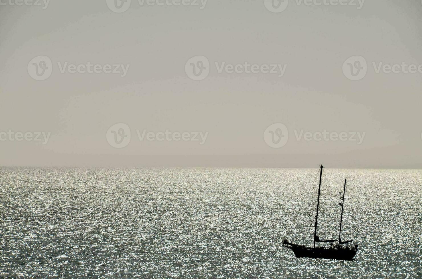 a sailboat is seen in the distance on the ocean photo