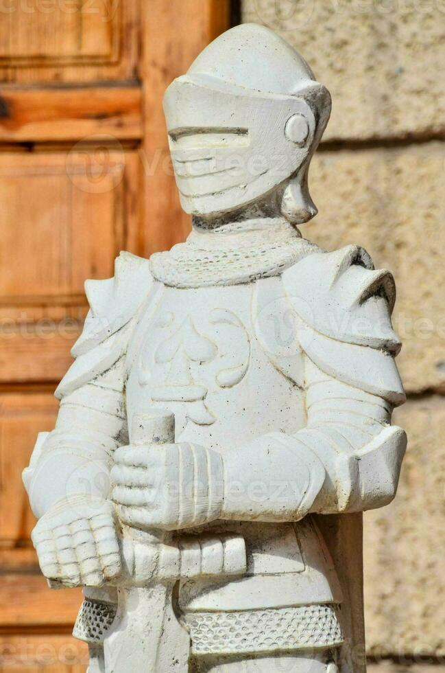 a statue of a knight in armor stands outside photo