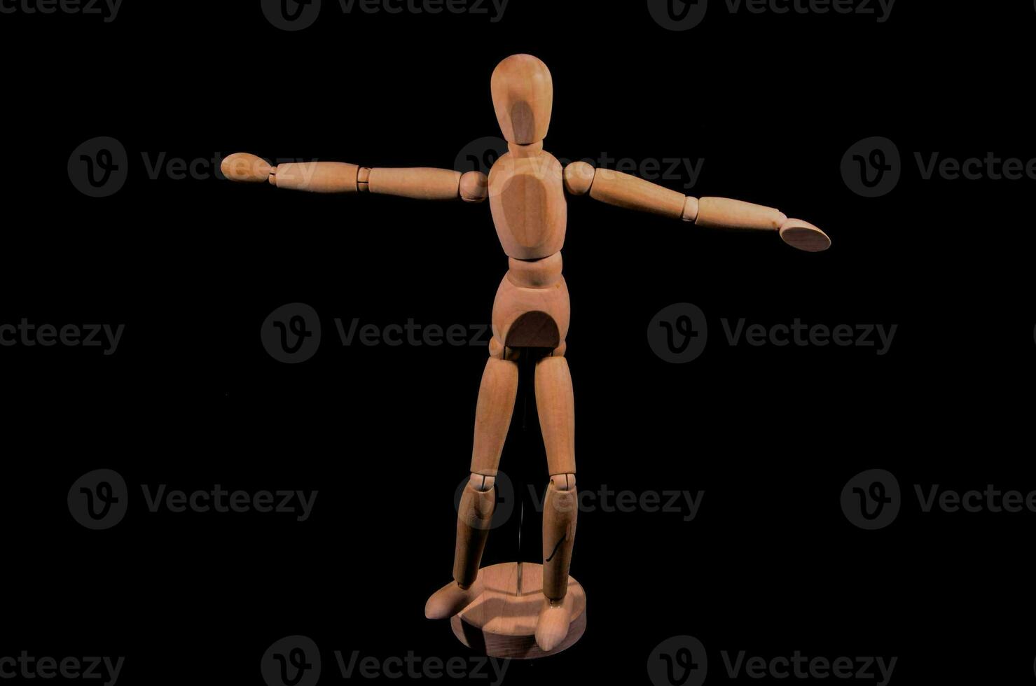 wooden mannequin with arms outstretched on a black background photo