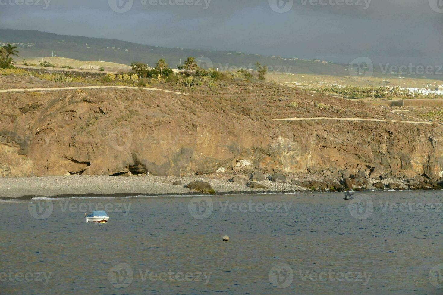 a boat is sitting on the beach near a cliff photo