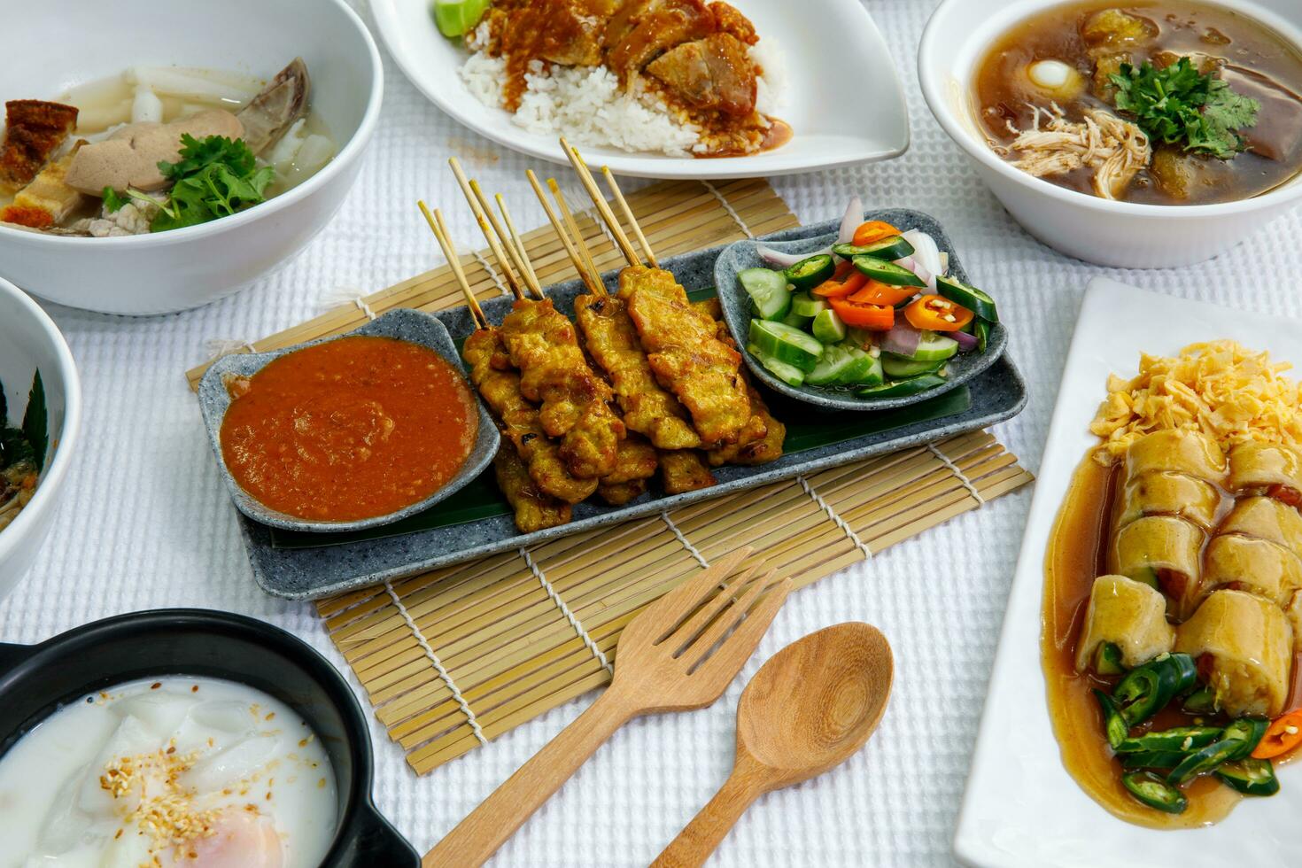 Pork Satay on plate. Grilled pork served with peanut dipping sauce,toasted bread and sweet sour sauce decorated with cucumber,onion and chili. One of the best Thai street food. photo