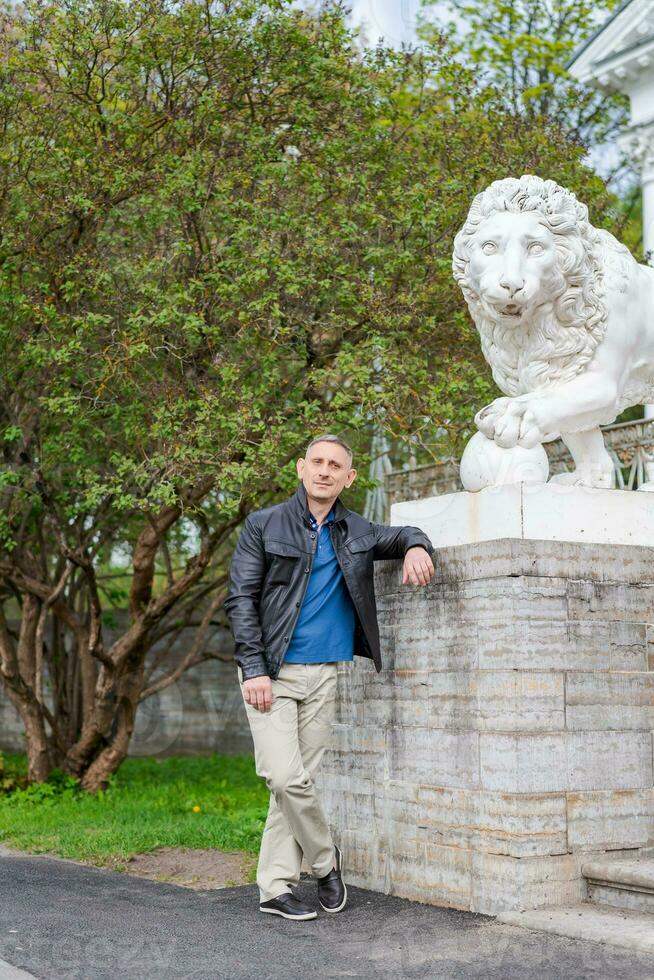 a man in casual clothes stands near a beautiful white building with lions photo