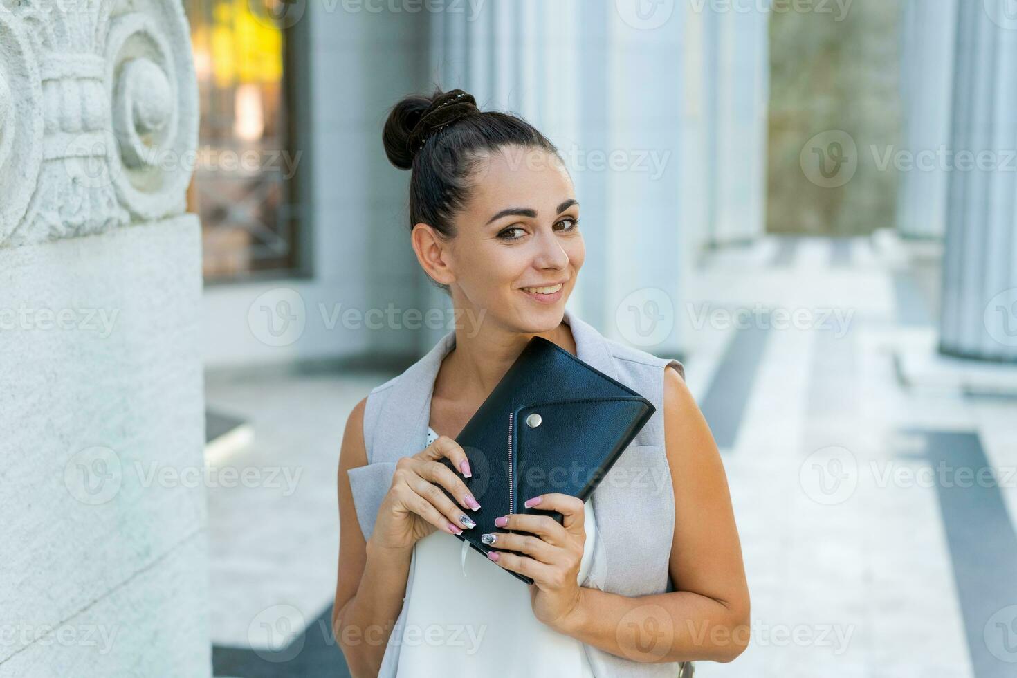 Beautiful woman smiling happy standing at city. Notepad in hand standing photo