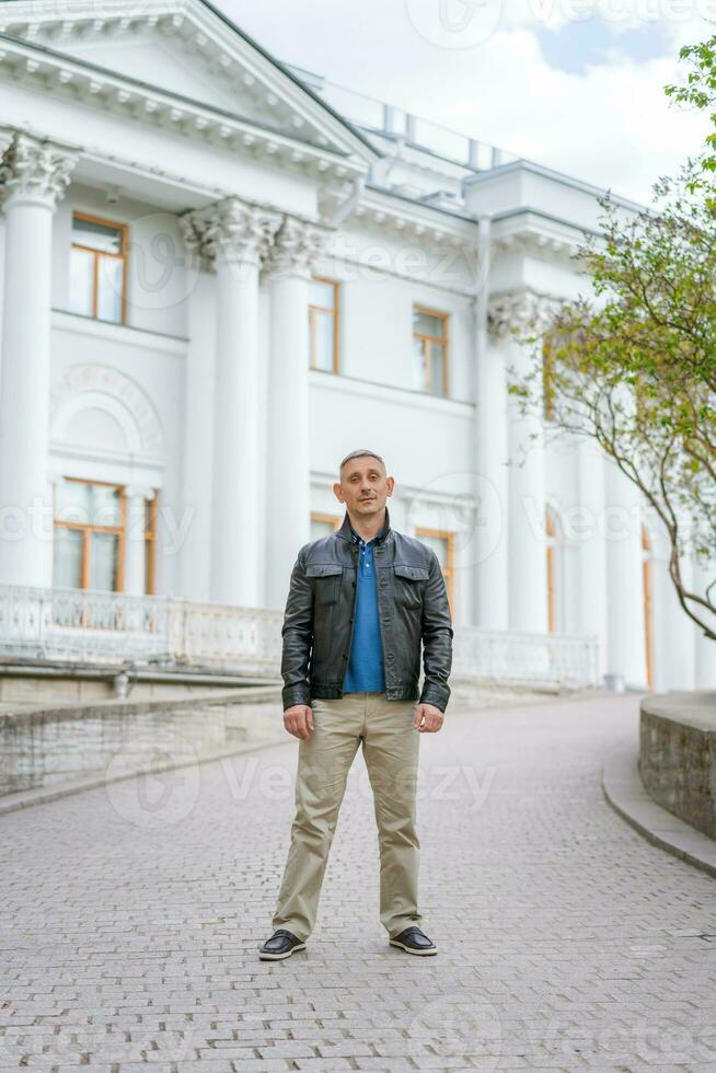 a man in casual clothes stands near a beautiful white building photo
