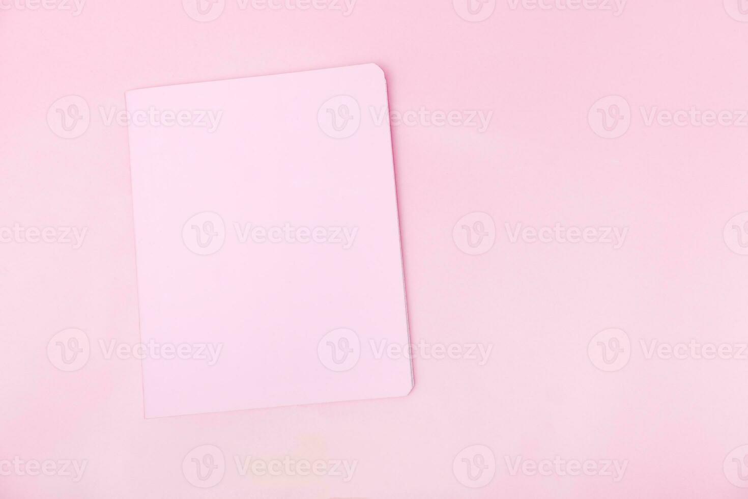 Top view photo workplace with a pink notebook, on an isolated pink background, copy space. female business concept