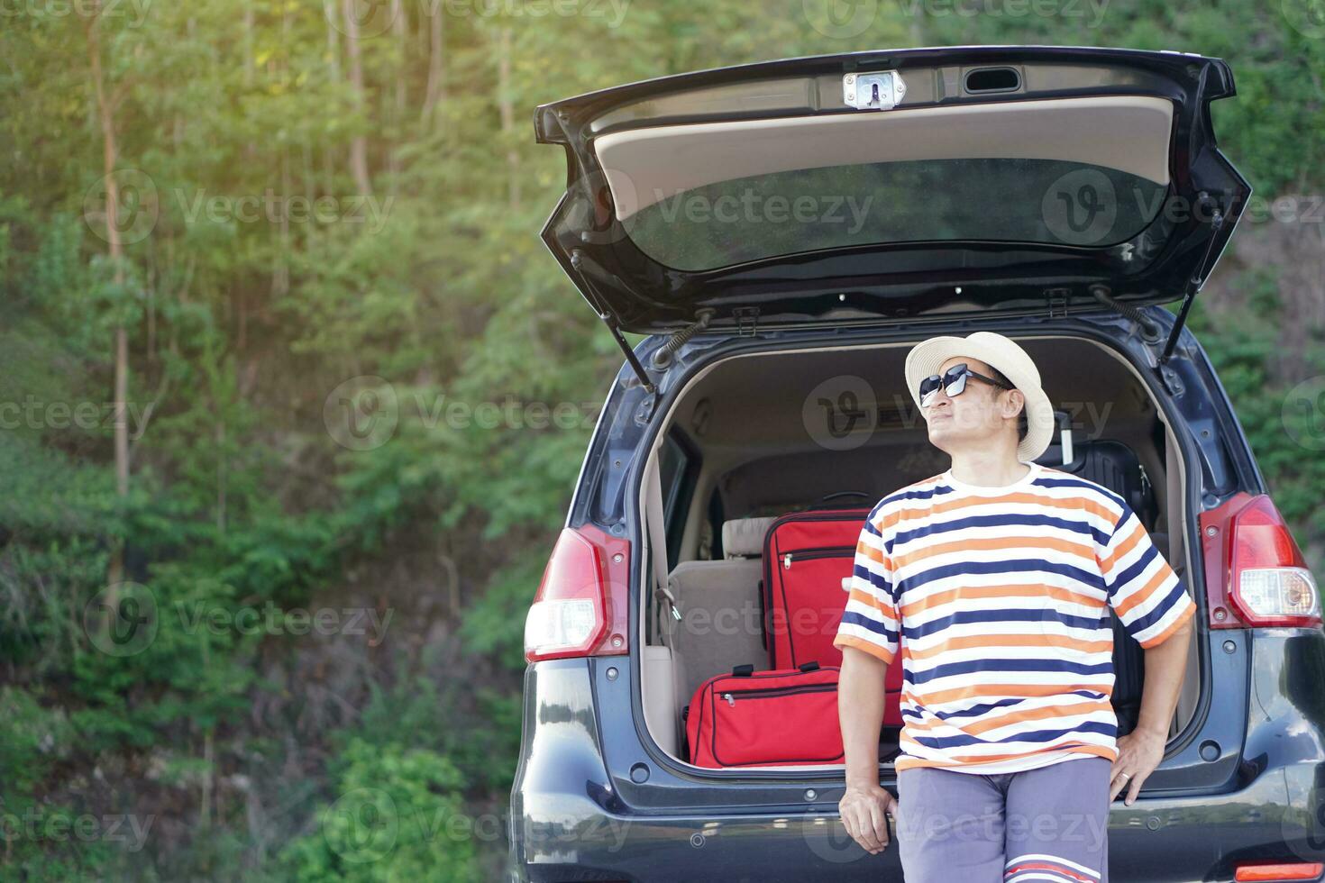 Asian man traveler sit on trunk of car with suitcases. Concept, relax time. Vacation or holiday trip by private vehicle. Transportation. Give time for yourself. photo