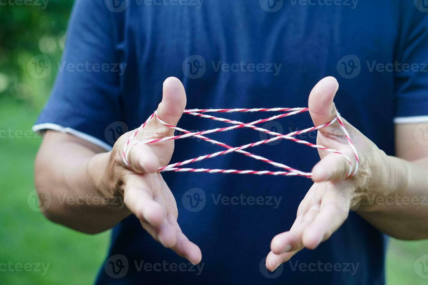 Closeup boy hands is playing rope which called cats cradle game. Concept, game involving the creation of various style figures between the fingers. Traditonal playing. photo