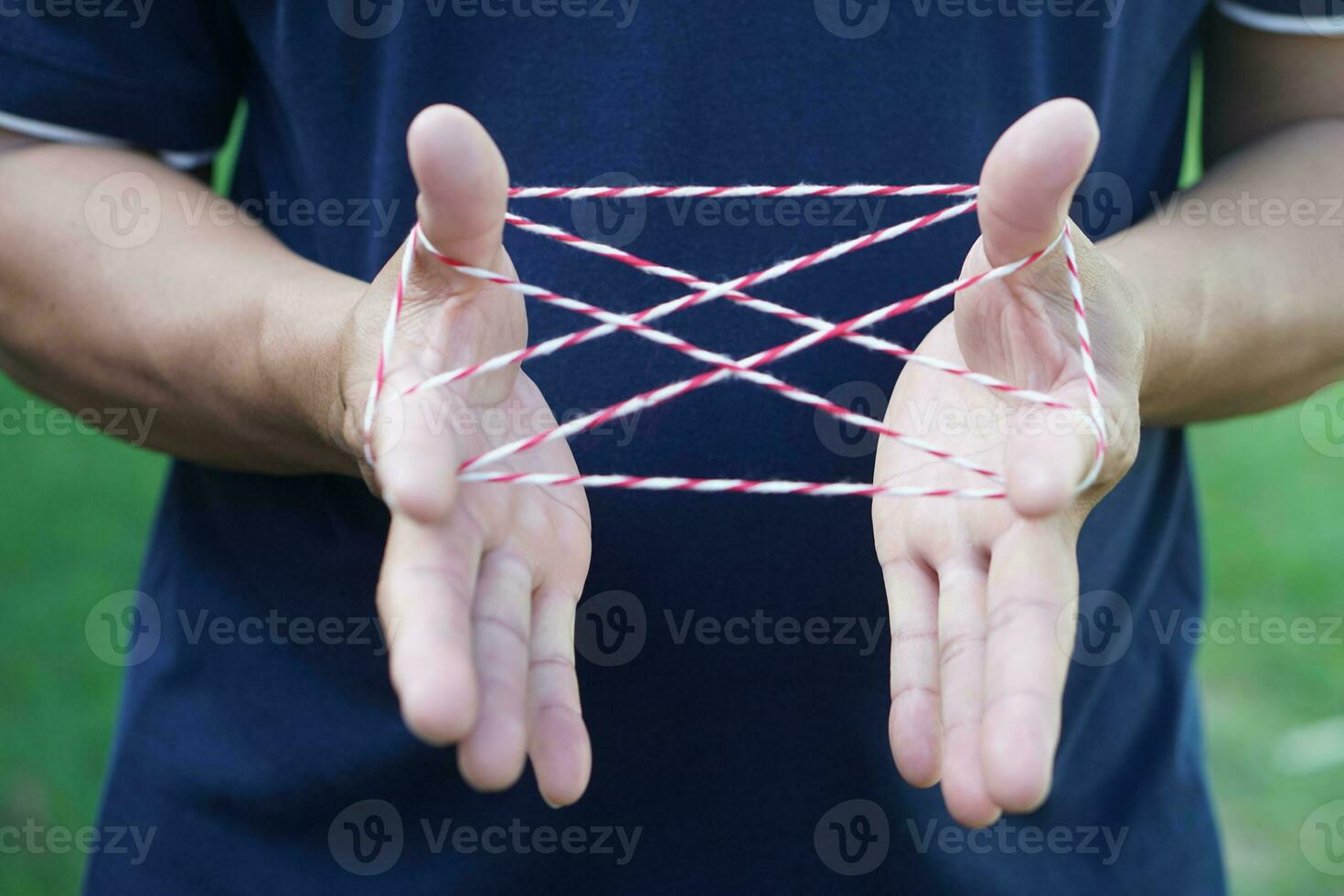 Closeup boy hands is playing rope which called cats cradle game. Concept, game involving the creation of various style figures between the fingers. Traditonal playing. photo