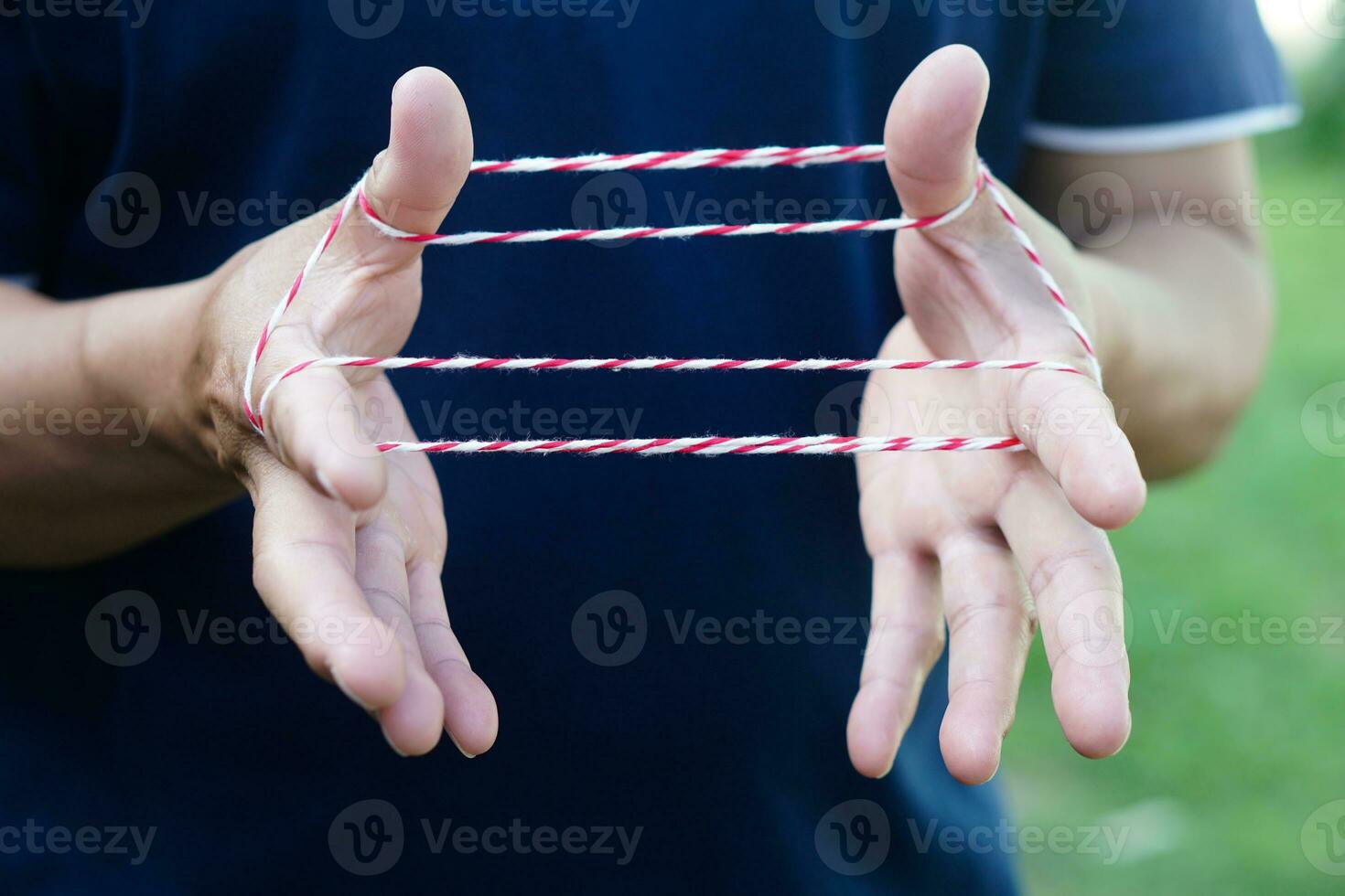 Closeup boy hands is playing rope which called cats cradle game. Concept, game involving the creation of various style figures between the fingers. Traditonal playing. photo