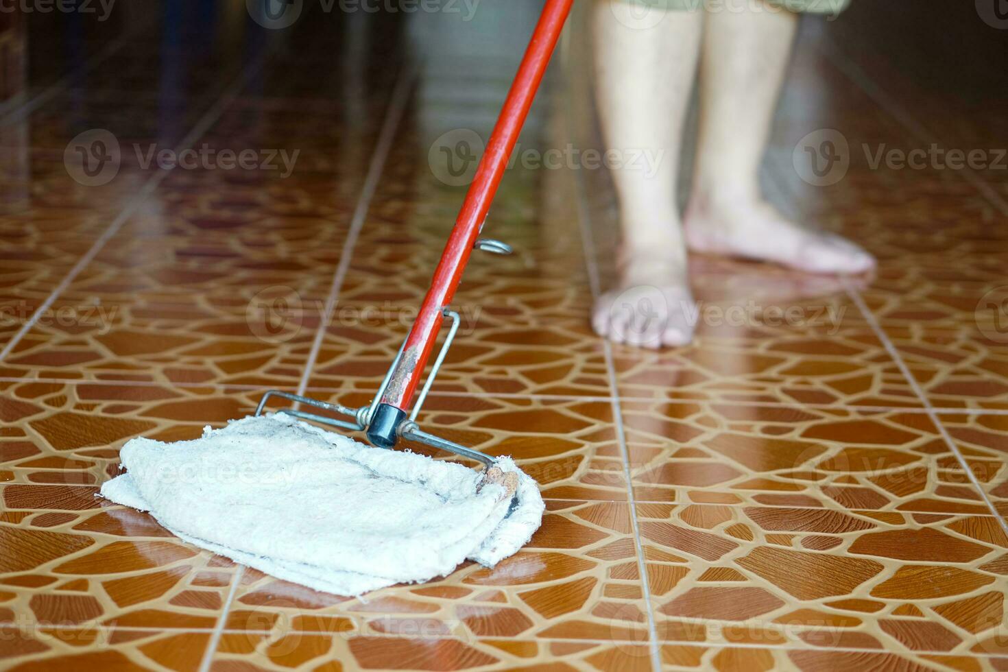 Close up man use a mop by using old towel to mop the floor. Concept, household chore in daily life. Hygienic and sanitary. Mop the dust, wipe the floor. Cleaning house. Maintaining tile floors. photo