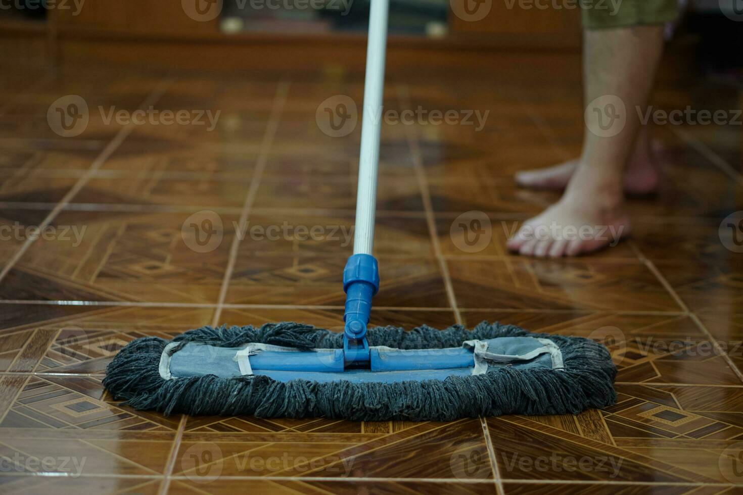 Close up man use a mop to mop the floor. Concept, household chore in daily life. Hygienic and sanitary. Mop the dust, wipe the floor. Cleaning house. Maintaining tile floors to be clean and shiny photo