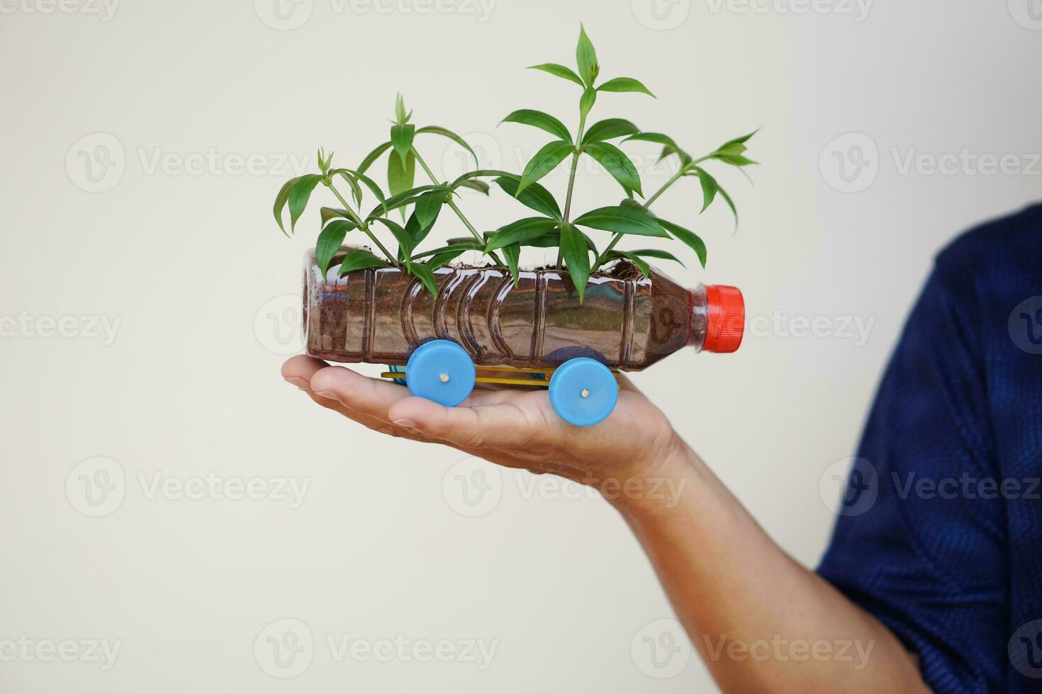Close up hand hold DIY car which grow plants, made from plastic bottle and caps. Concept, Gardening from recycle crafts. Reduce, reuse and recycle plastic garbage photo
