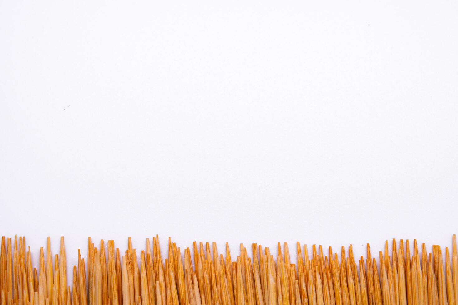 Toothpicks arranged in a long line in a white scene photo