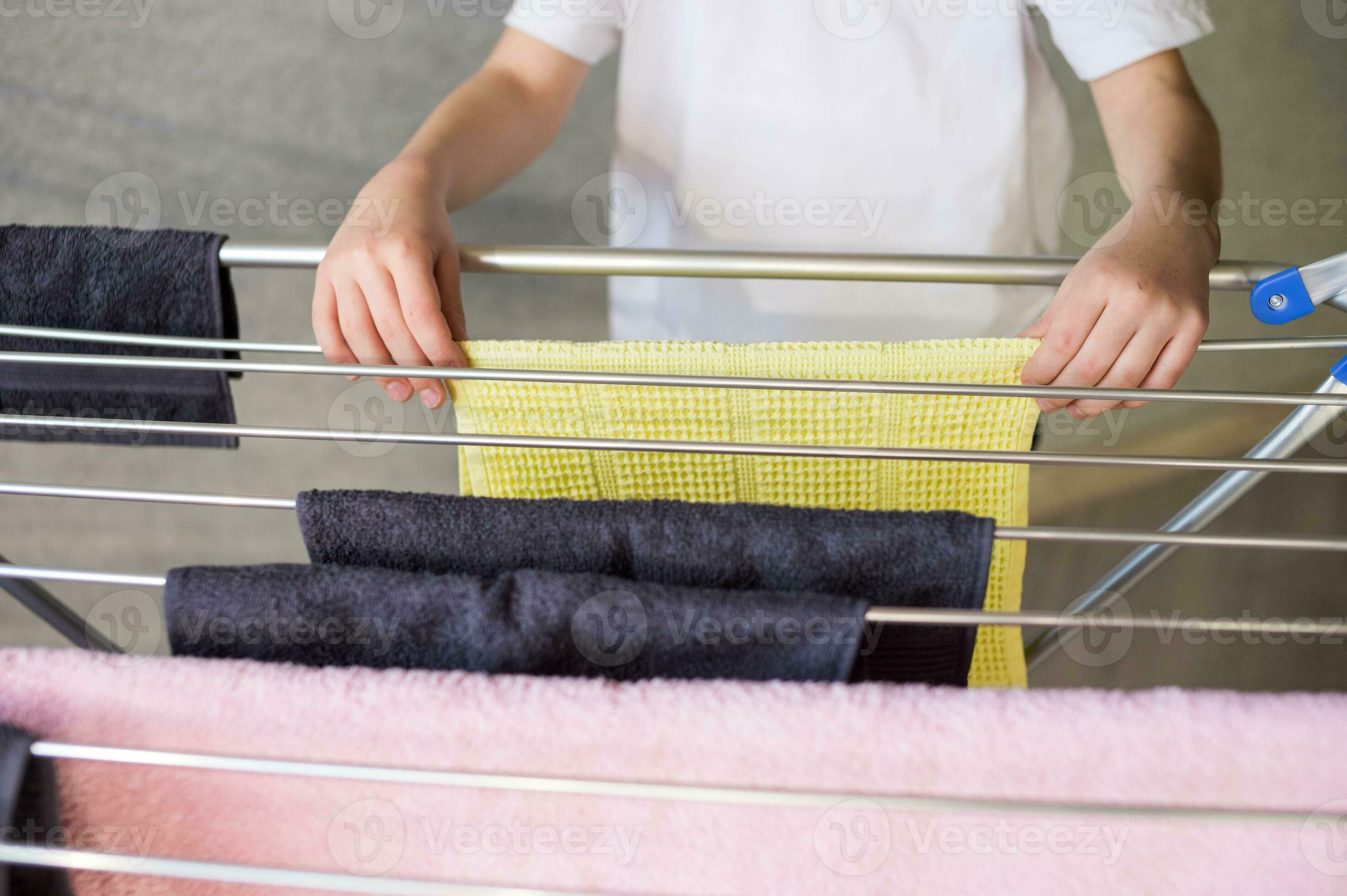 Cute boy hangs a wet towel on a metal clothes dryer, housework, child's