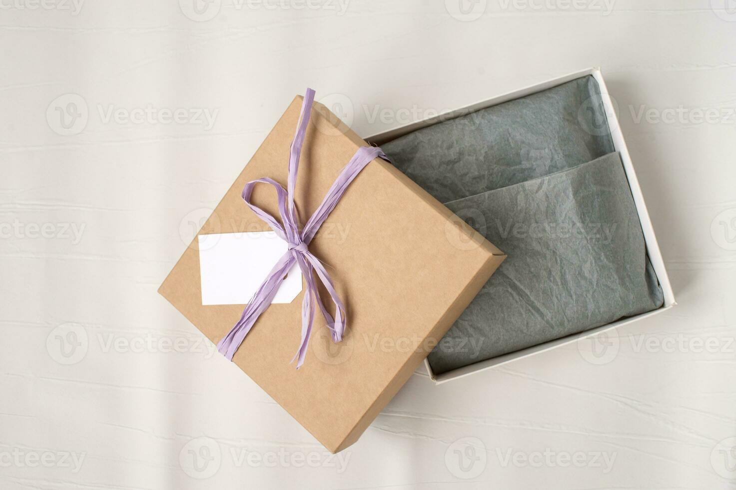 Open brown gift square craft box with ribbon, mockup tag, price tag. Paper for packaging clothes photo