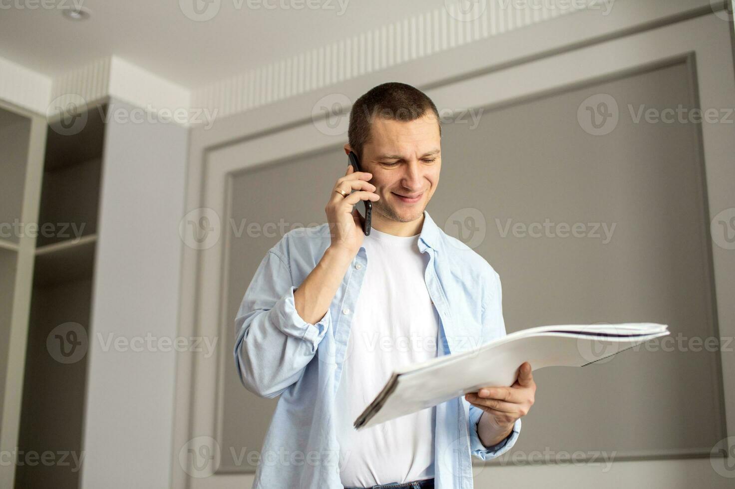 A cheerful man looks at an album and makes a call on the phone. Indoor repair work photo