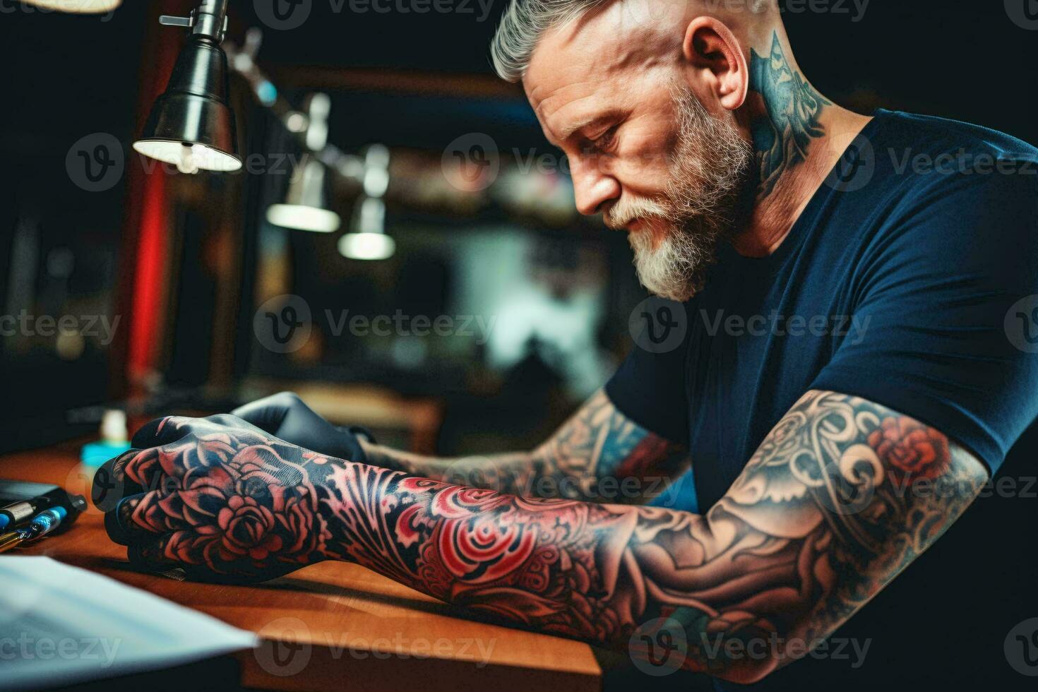 A tattooed man working on a laptop at a desk AI Generated photo