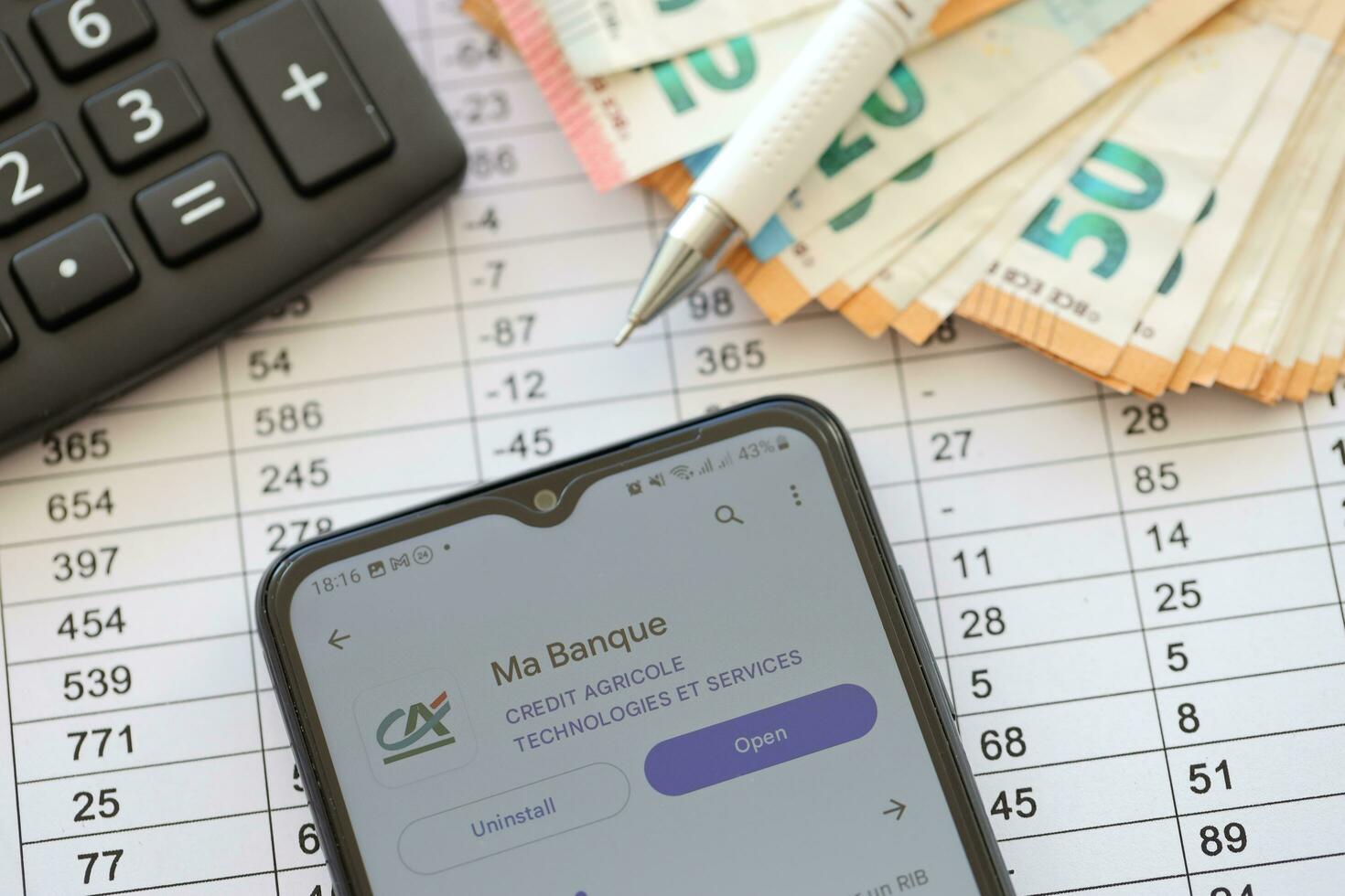 TERNOPIL, UKRAINE - AUGUST 3, 2023 Credit Agricole CA application on screen on modern smartphone and many bills of euro currency photo