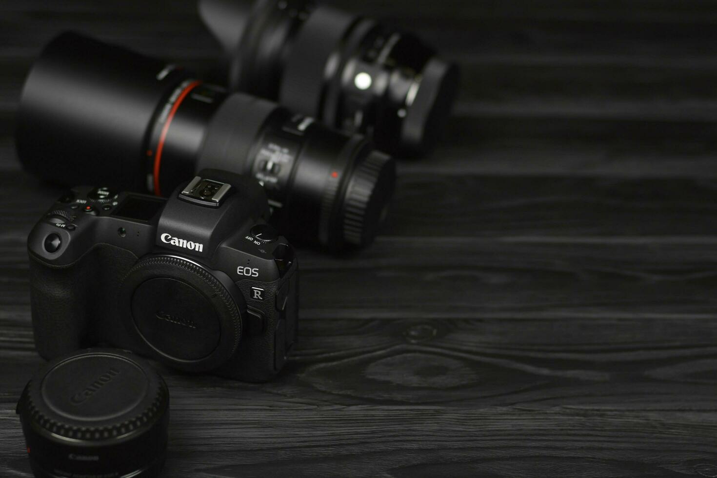 Canon EOS R photocamera and mount adapter EF - EOS R with Canon 105mm f2.8 and Sigma 24-105 f4 Art lenses on black wooden table photo