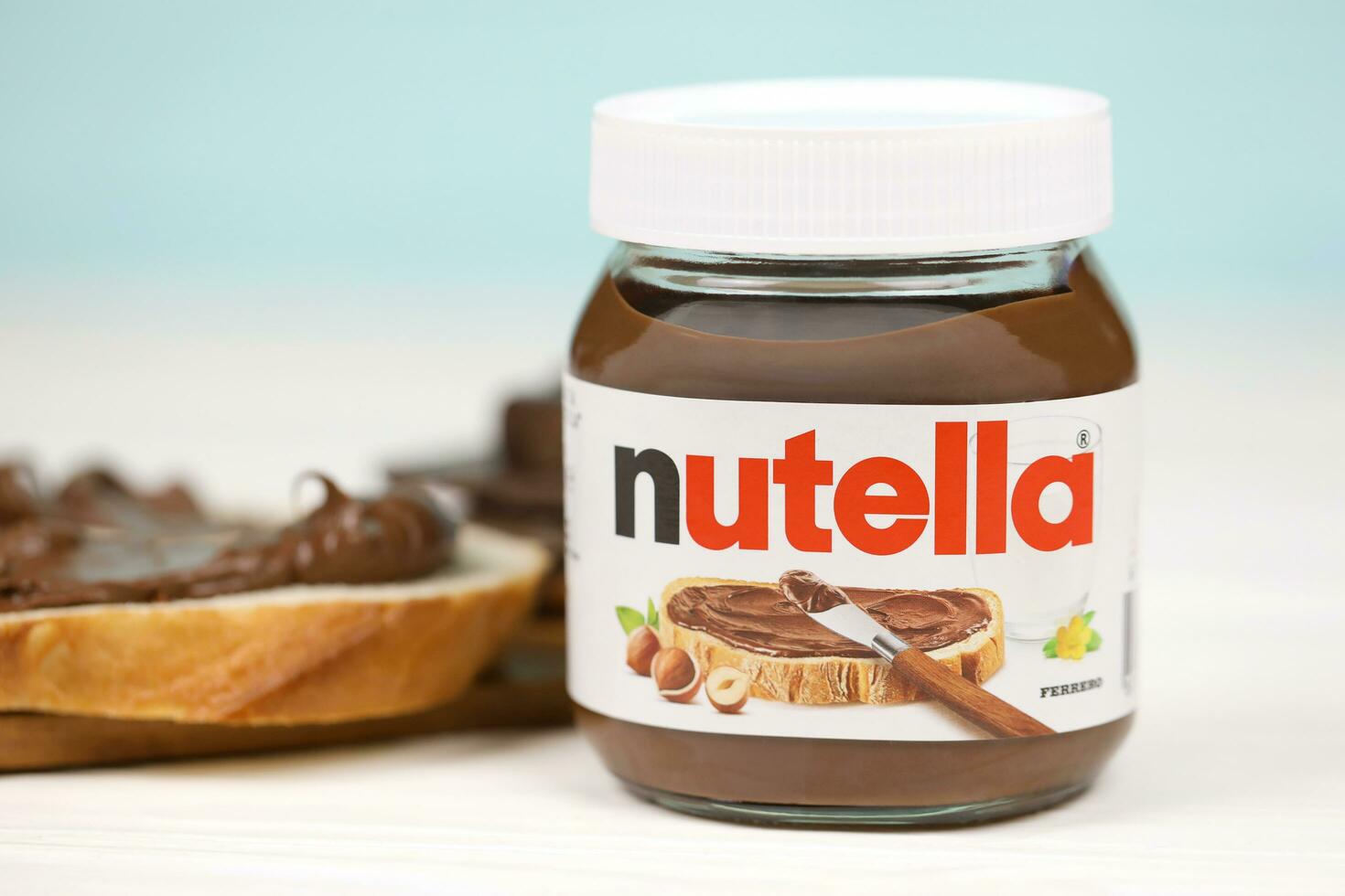 KHARKOV, UKRAINE - DECEMBER 27, 2020 Nutella glass can and spread on freshly baked bread. Nutella is manufactured by Italian company Ferrero first introduced in 1964 photo
