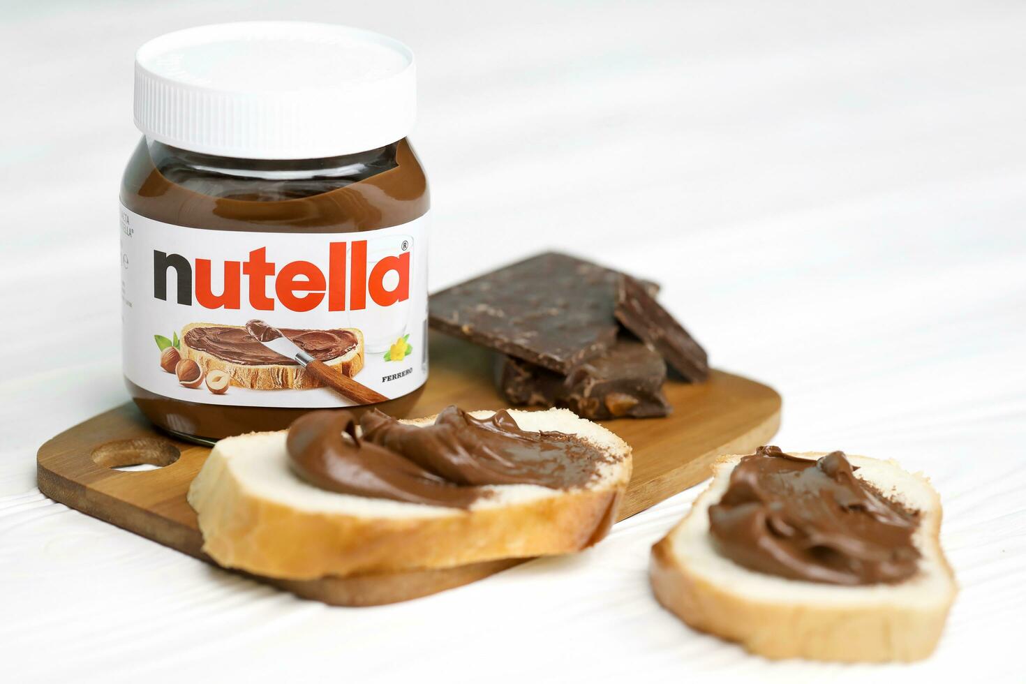 KHARKOV, UKRAINE - DECEMBER 27, 2020 Nutella glass can and spread on freshly baked bread. Nutella is manufactured by Italian company Ferrero first introduced in 1964 photo