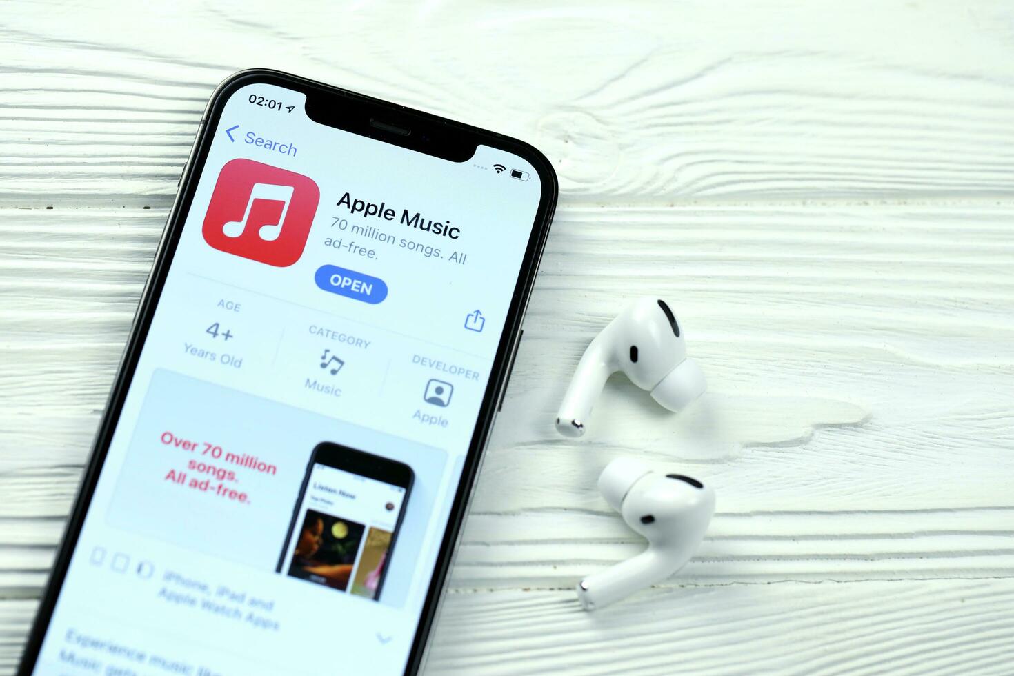KHARKOV, UKRAINE - MARCH 5, 2021 Apple music icon and application from App store on iPhone 12 pro display screen with airpods pro on white table photo