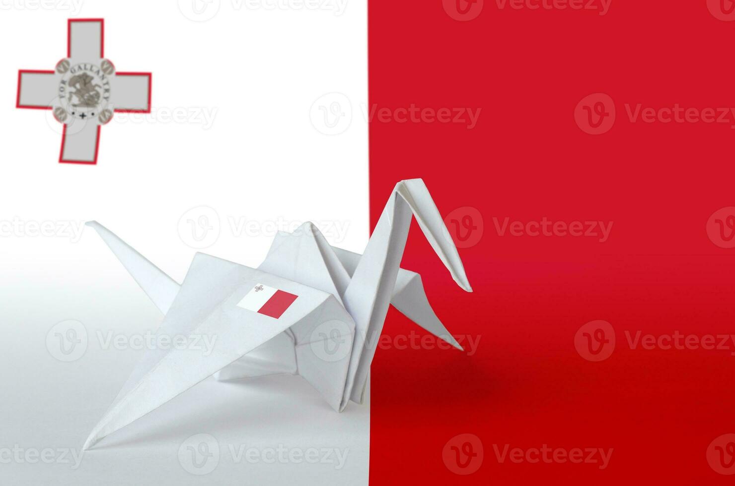 Malta flag depicted on paper origami crane wing. Handmade arts concept photo