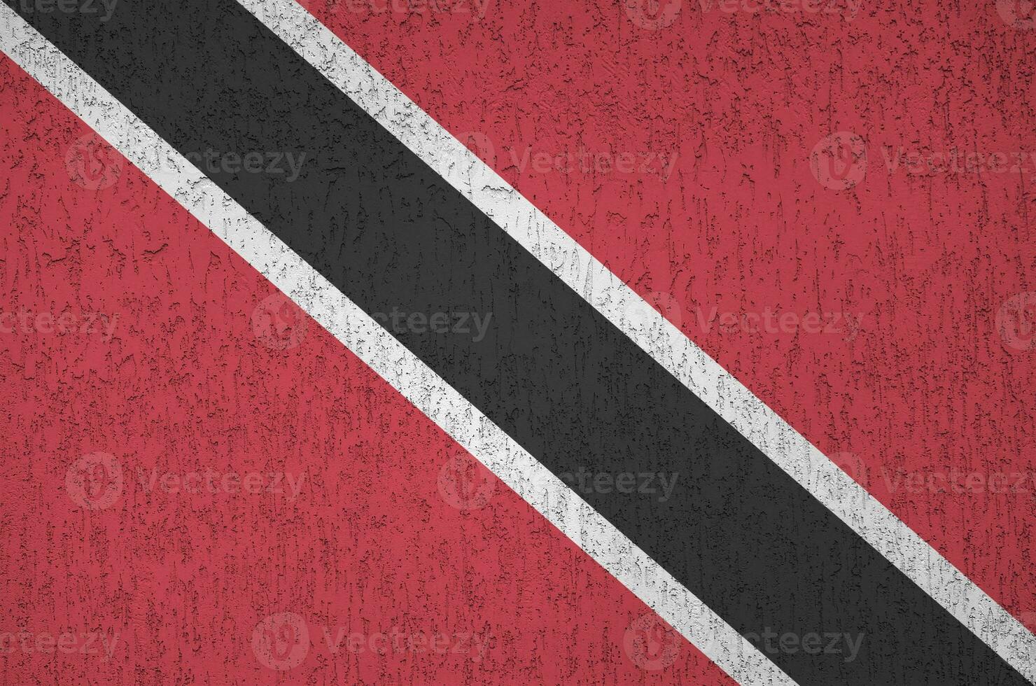 Trinidad and Tobago flag depicted in bright paint colors on old relief plastering wall. Textured banner on rough background photo