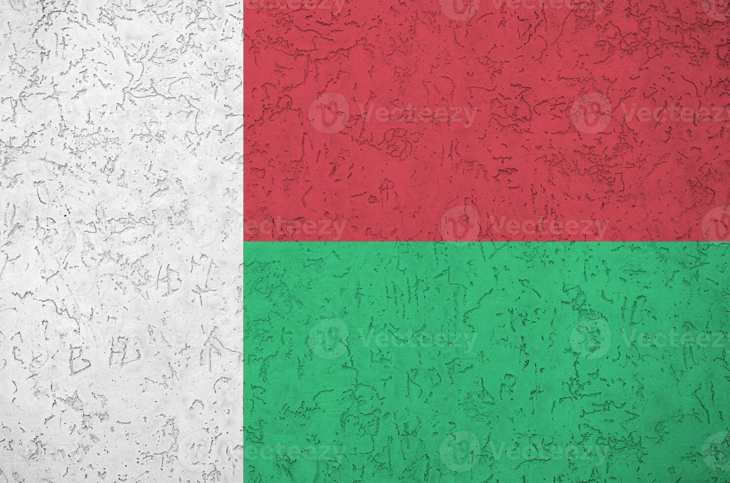 Madagascar flag depicted in bright paint colors on old relief plastering wall. Textured banner on rough background photo