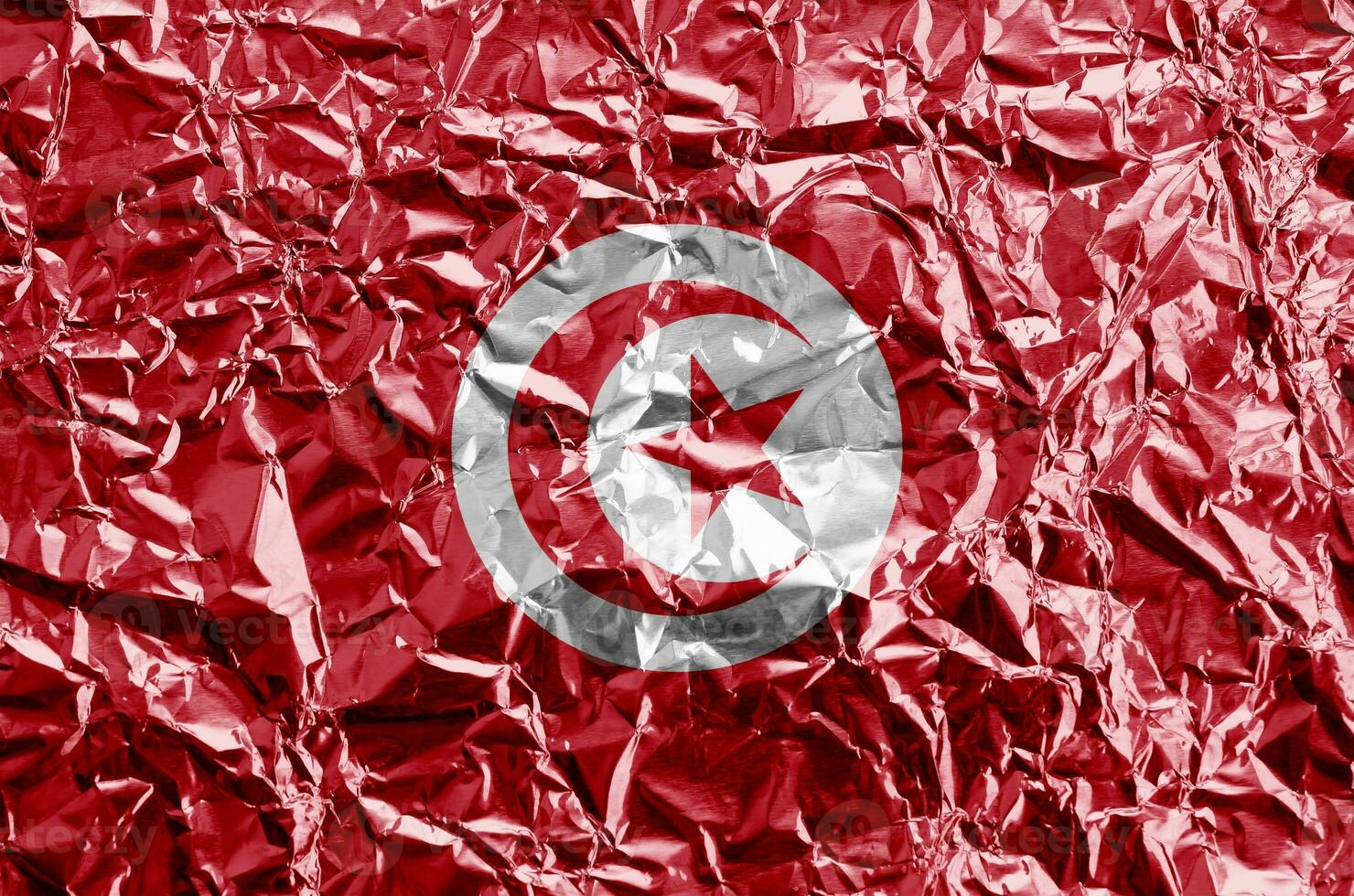 Tunisia flag depicted in paint colors on shiny crumpled aluminium foil closeup. Textured banner on rough background photo