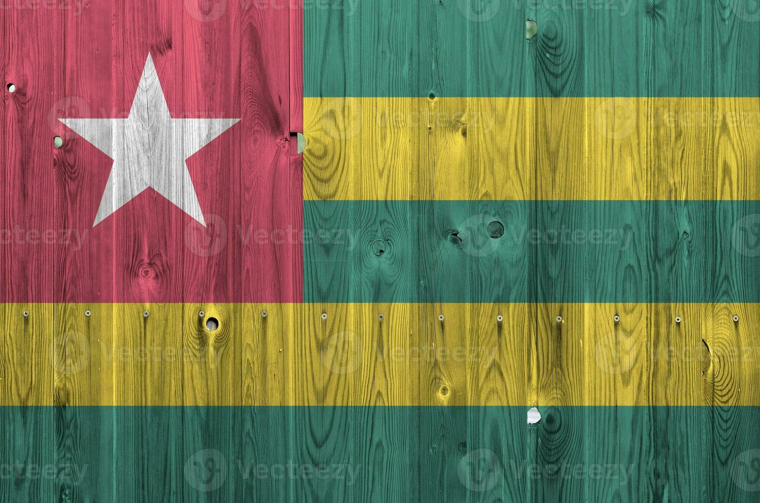 Togo flag depicted in bright paint colors on old wooden wall. Textured banner on rough background photo