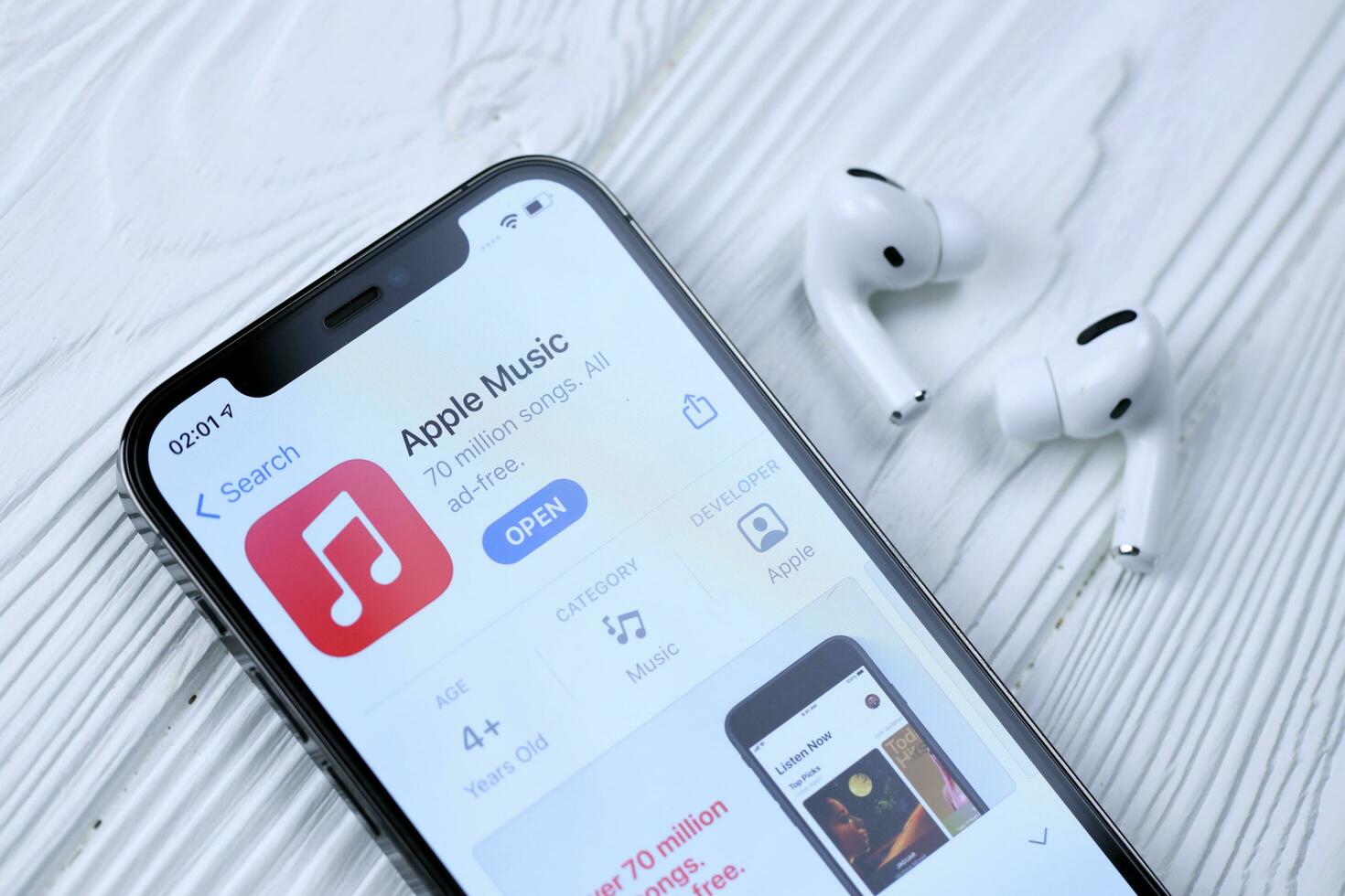 KHARKOV, UKRAINE - MARCH 5, 2021 Apple music icon and application from App store on iPhone 12 pro display screen with airpods pro on white table photo