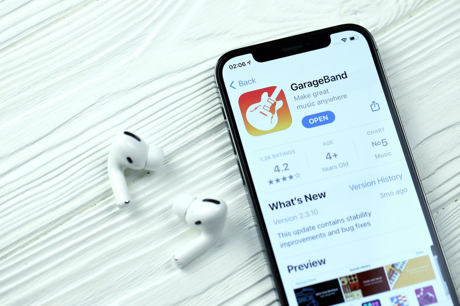 KHARKOV, UKRAINE - MARCH 5, 2021 Garageband for artists icon and application from App store on iPhone 12 pro display screen with airpods pro on white table photo
