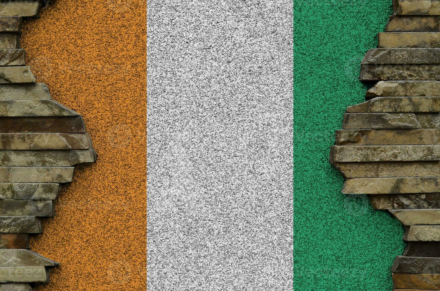 Ivory Coast flag depicted in paint colors on old stone wall closeup. Textured banner on rock wall background photo