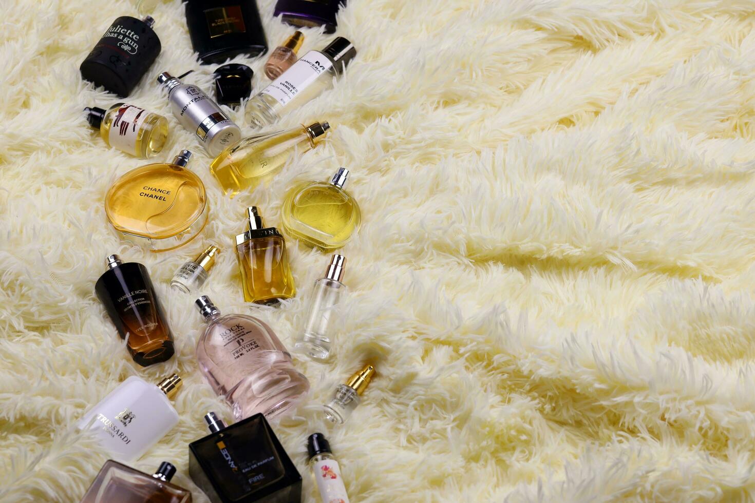 KHARKOV, UKRAINE - JANUARY 12, 2021 Many perfume bottles with famous brand names lies on fluffy beige plaid photo