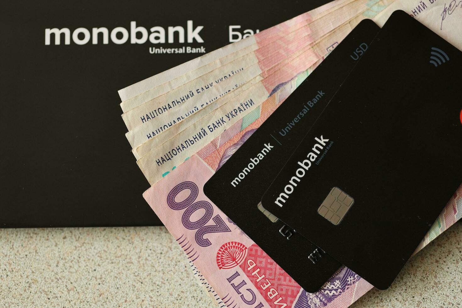 KYIV, UKRAINE - JULY 7, 2023 Monobank banking plastic cards with money on table photo