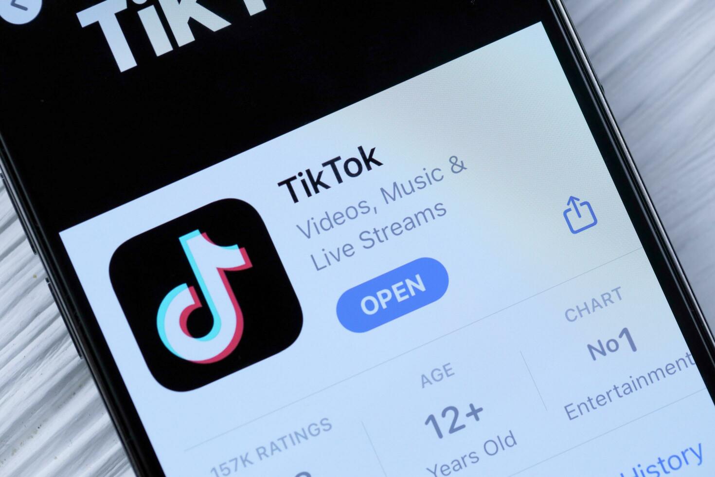 KHARKOV, UKRAINE - MARCH 5, 2021 Tiktok icon and application from App store on iPhone 12 pro display screen on white table photo