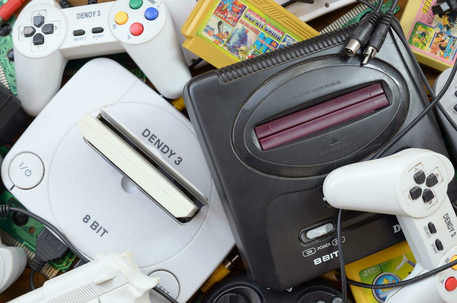 Pile of old 8-bit video game consoles and many gaming accessories like a joysticks and cartridges photo