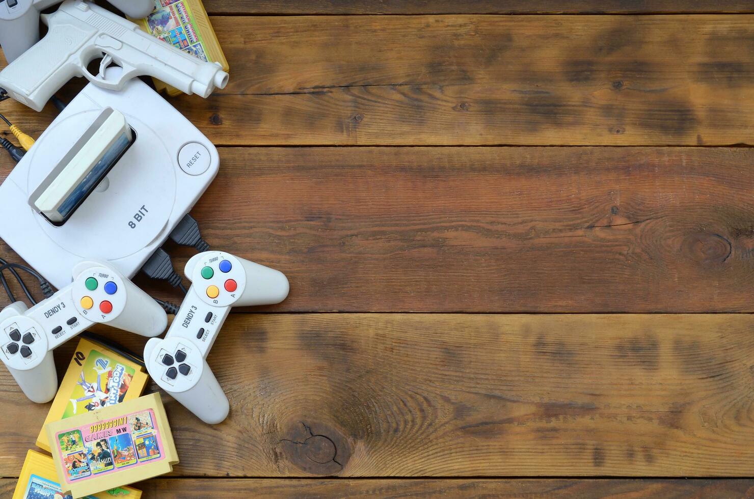 Old 8-bit video game console and many gaming accessories like a joysticks and cartridges photo