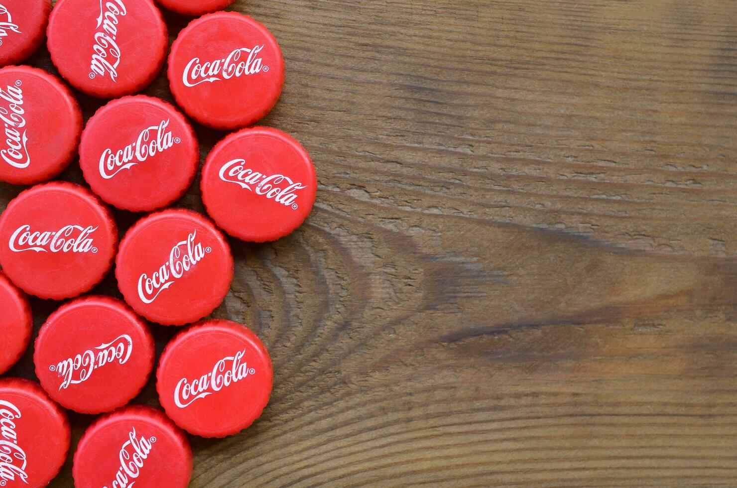 Many red caps with coca cola logo on wooden background photo