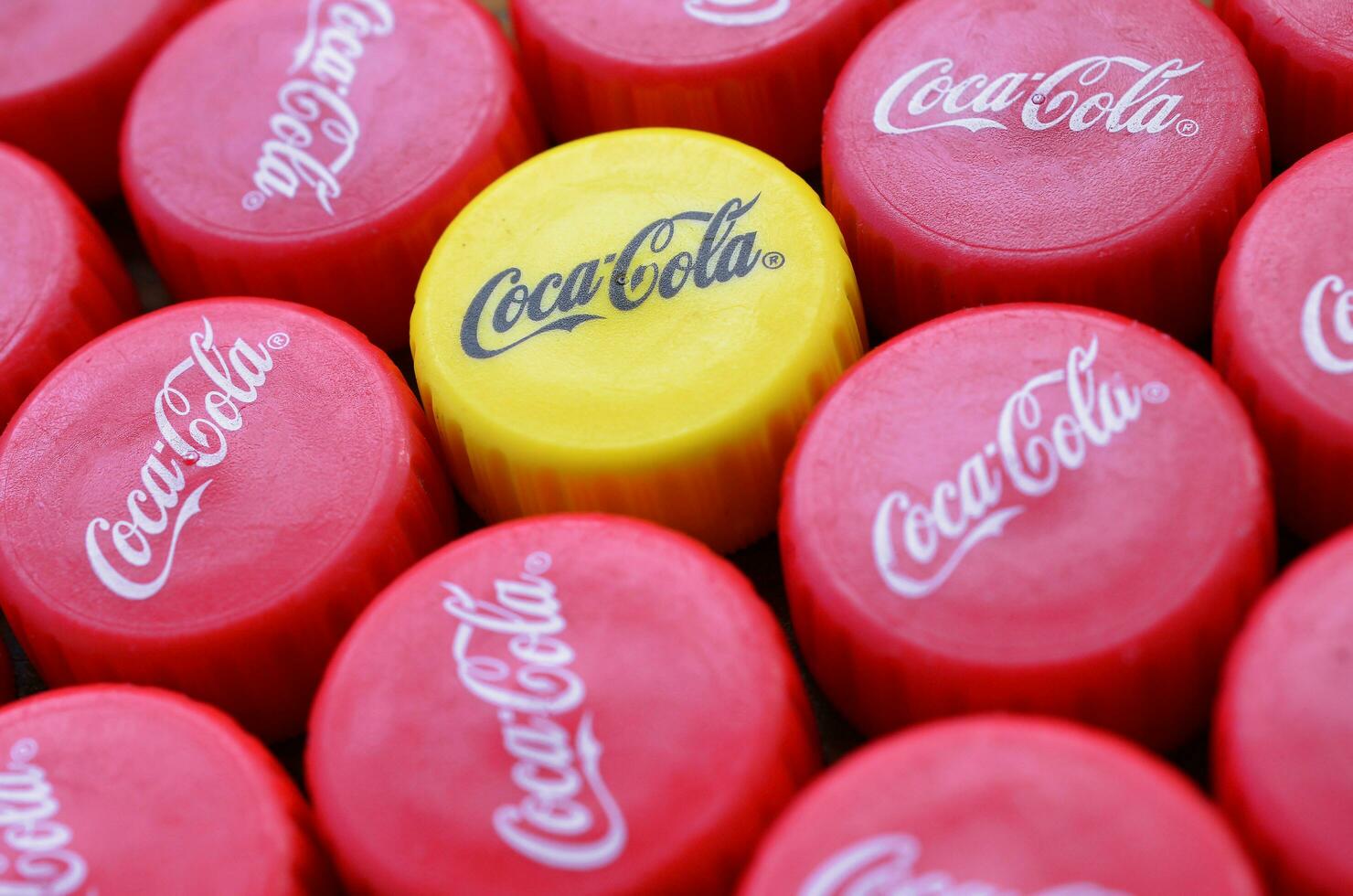 Many red lids and one yellow plastic cap with coca cola logo close up photo