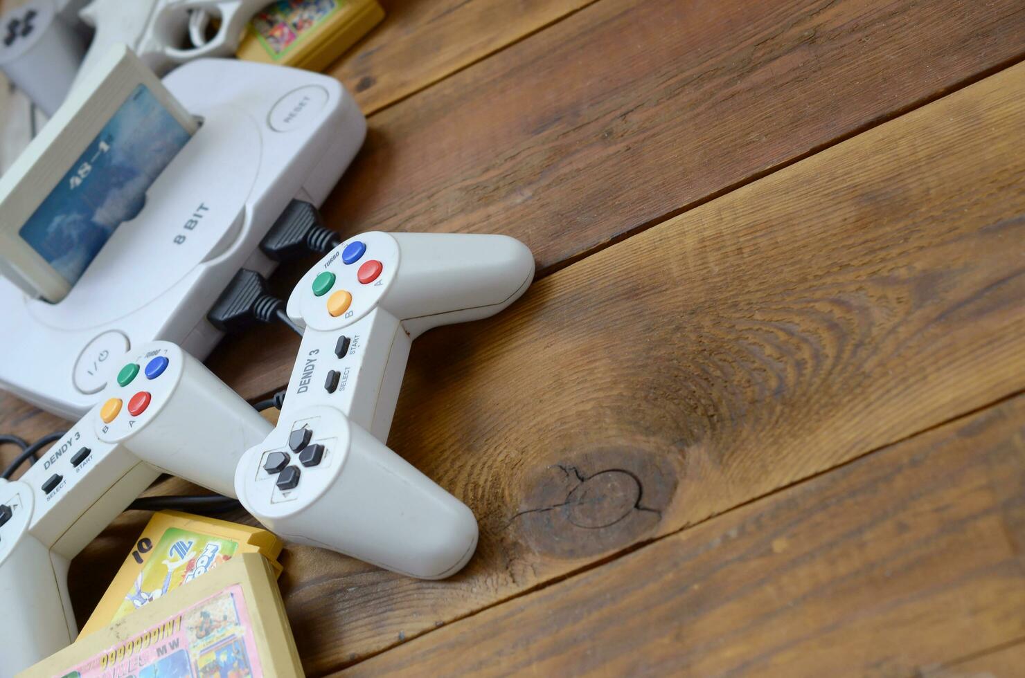Old 8-bit video game console and many gaming accessories like a joysticks and cartridges photo