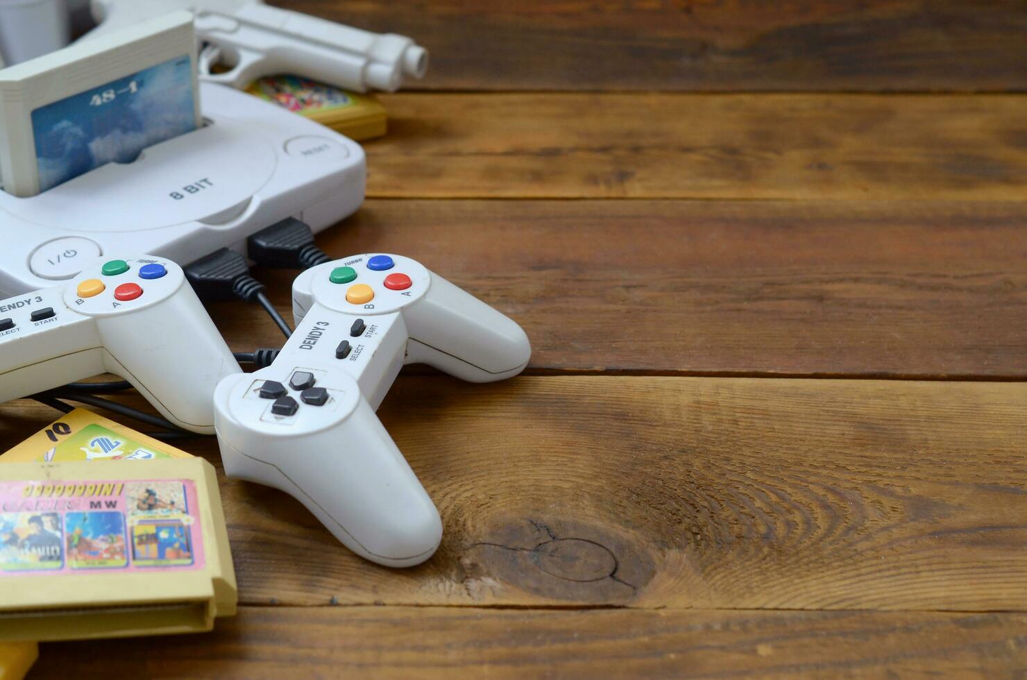 Old 8-bit video game console and many gaming accessories like a joysticks and cartridges photo