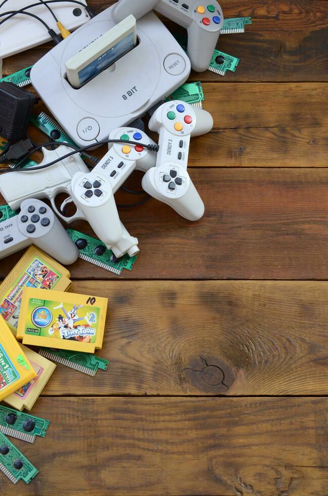 Old 8-bit video game console and many gaming accessories like a joysticks and cartridges photo
