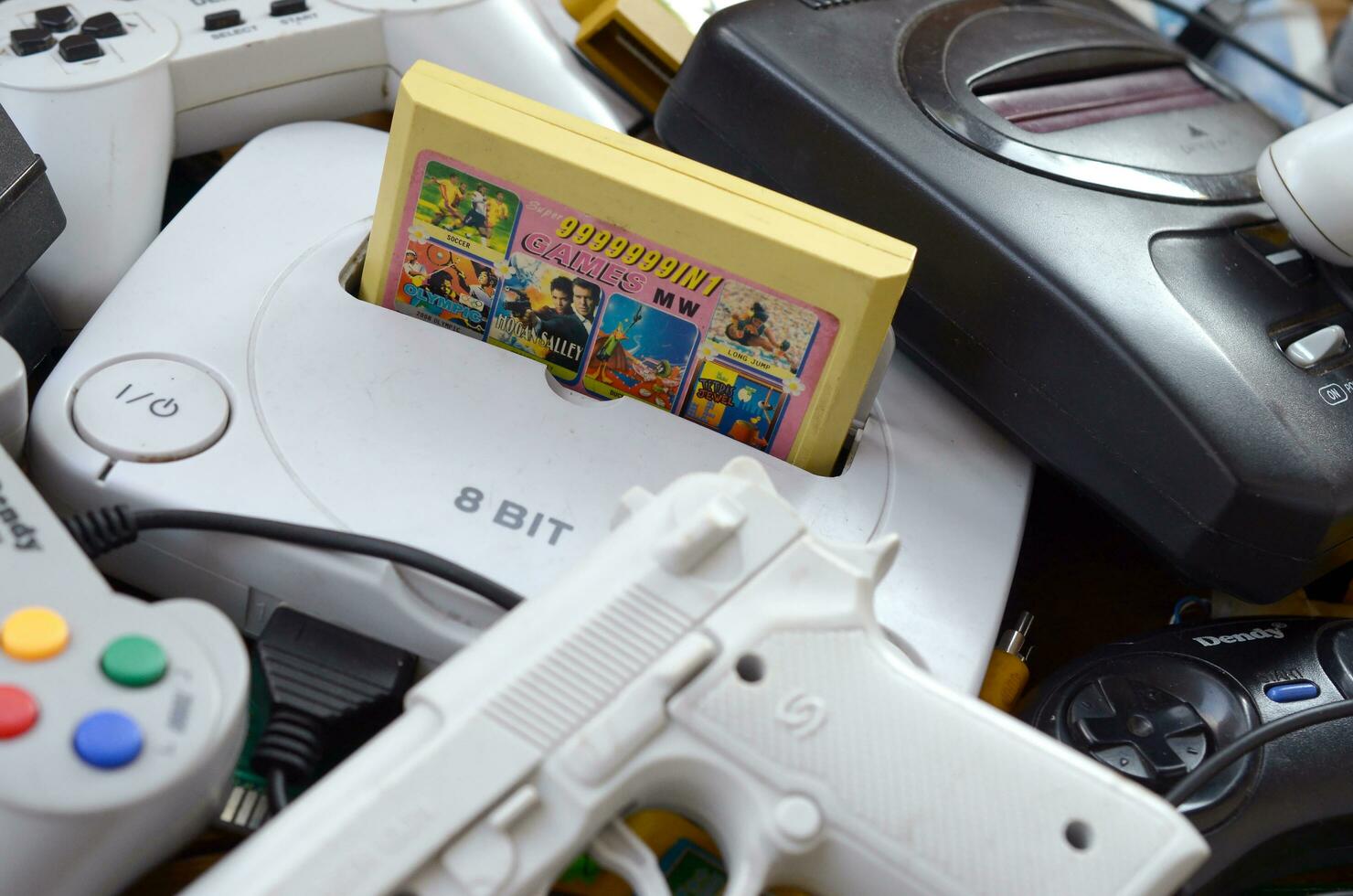 Pile of old 8-bit video game consoles and many gaming accessories like a joysticks and cartridges photo